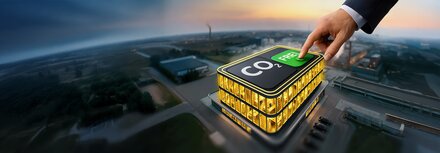 Einladung zum Business-Event – live im GOP Bremen Ein erleuchtetes Gebäude aus der Luft bei Nacht, das von einer Hand aus der Luft im Anzugärmel berührt wird, auf dem Dach steht CO2-frei