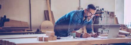 Ein Handwerker mit Laptop und Tablet an der Werkbank