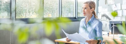 Direktvermarktung mit Redispatch 2.0 Eine Frau in einem Büro, die Unterlagen in den Händen hält.