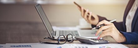 Rechnungserklärung online Ein Bürotisch mit Computer, Taschenrechner und Brille
