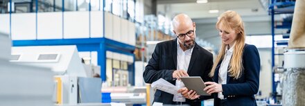 EWE business Gas für mittlere und größere Unternehmen Eine Frau und ein Mann prüfen etwas auf einem Tablet in einer Produktionshalle
