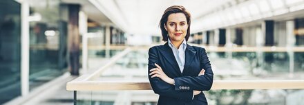 Eine Frau in einem Unternehmensgebäude, die die Arme verschränkt