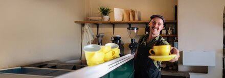 Ein Barista in einem Café, der eine gelbe Kaffeetasse reicht
