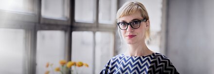 Entwicklung der Energiepreise Eine Frau mit Brille guckt in die Kamera, dahinter eine Fensterfront