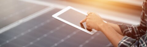 Marktstammdatenregister Eine Person bedient ein Tablet, im Hintergrund PV-Module