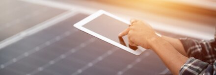 Marktstammdatenregister Eine Person bedient ein Tablet, im Hintergrund PV-Module