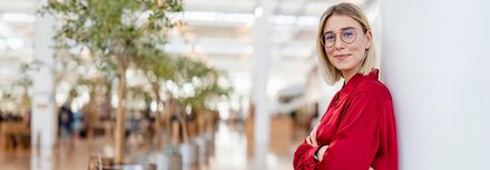 Digitaler Stromzähler Eine junge Frau mit Brille, die sich an eine Wand anlehnt und lächelt