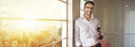 EWE business Wärme Ein Mann im weißen Hemd in einem Bürohochhaus, in das die Sonne scheint