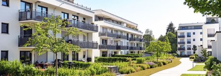 EWE business Fernwärme Weiße Mehrfamilienhäuser mit begrünten Wegen