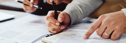 Förderantrag für energetische Maßnahmen Die Hände von Personen, die in Unterlagen etwas eintragen