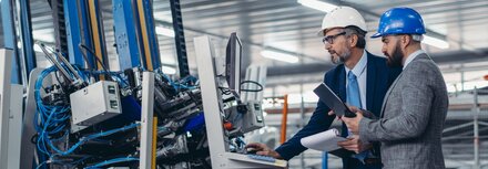 Digitale Vernetzung mit ENX von EWE Zwei Männer mit Helmen in Produktionshalle