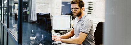 LAN-Lösungen von EWE Mann mit Brille in Großraumbüro am Computer