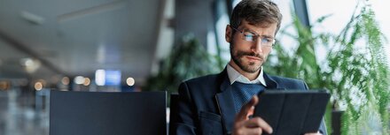 SOC-Whitepaper Ein Mann im Jacket und mit Brille liest etwas auf einem Tablet.