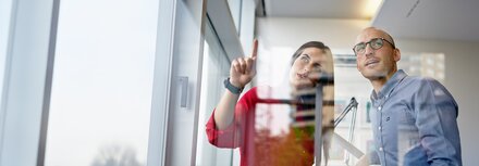 Lesen Sie das Whitepaper über SASE Mann und Frau betrachten etwas im Büro