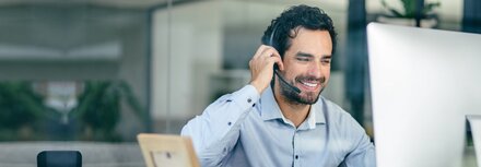 Session Border Controller Mann im Büro mit Headset vor einem Bildschirm