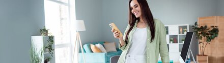 Braunhaarige Frau mit Smartphone in der Hand