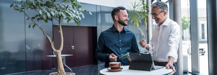 Zwei Männer unterhalten sich an einem Stehtisch in einem Unternehmen.