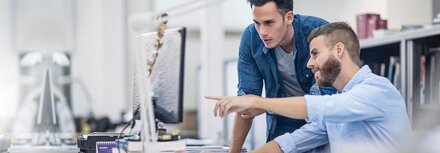 Phishing-Check von EWE Ein Mann zeigt einem Kollegen etwas am Computer-Bildschirm