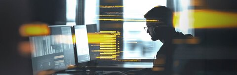 IT-Security mit EWE business Ein Mann arbeitet in einem abgeschatteten Büro an einem Computer.