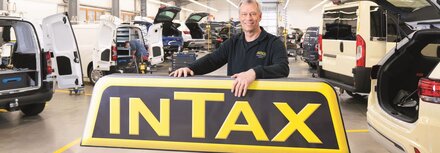 EWE business Referenz INTAX Mann vor Firmenschild "INTAX"