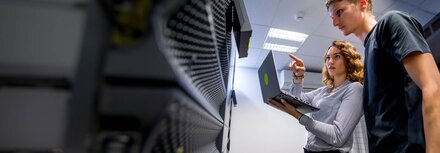 Sichere & leistungsfähige Infrastruktur Eine Frau mit Laptop zeigt einem Kollegen etwas vor einem Server.