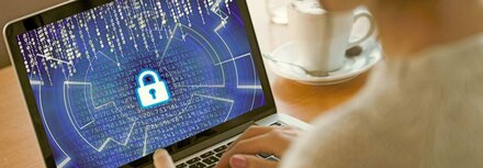 Daten-Backups Eine Frau versucht, ein Notebook zu entsperren, auf dem Code zu erkennen ist, im Hintergrund eine Kaffeetasse