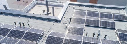 PV-Energie als Hebel für die Effizienzoptimierung von Unternehmen Solarpaneele auf einem Gebäude aus der Luft
