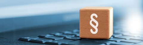 Gesetzesänderungen 2025 Ein Holzwürfel mit Paragraphenzeichen auf einer Tastatur