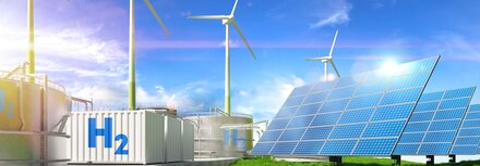 Windräder, PV-Anlagen, weiße Container mit H2-Aufschrift, vorne eine grüne Wiese