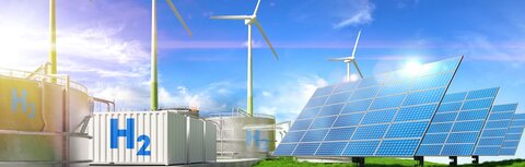 Windräder, PV-Anlagen, weiße Container mit H2-Aufschrift, vorne eine grüne Wiese