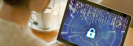 Interview mit ZAC-Experte Puschin zu Cyberkriminalität Eine Frau sitzt am Laptop und schaut auf den Bildschirm. Auf dem Bildschirm sind kryptische Zahlenkombinationen zu sehen und ein großes Schloss in der Mitte.