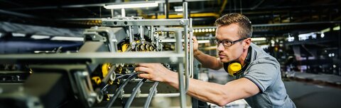 Beleuchtung und Arbeitsschutz Mitarbeiter nimmt Einstellungen an einer großen und gut beleuchteten Maschine vor.
