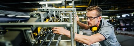 Beleuchtung und Arbeitsschutz Mitarbeiter nimmt Einstellungen an einer großen und gut beleuchteten Maschine vor.