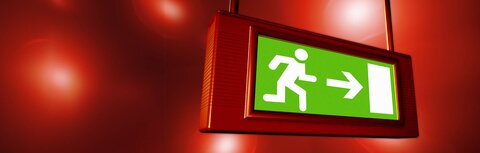 Sicherheitsfaktor Notbeleuchtung für Unternehmen Ein beleuchtetes Hinweisschild zeigt den Weg zum Notausgang