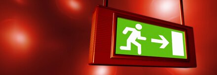 Sicherheitsfaktor Notbeleuchtung für Unternehmen Ein beleuchtetes Hinweisschild zeigt den Weg zum Notausgang