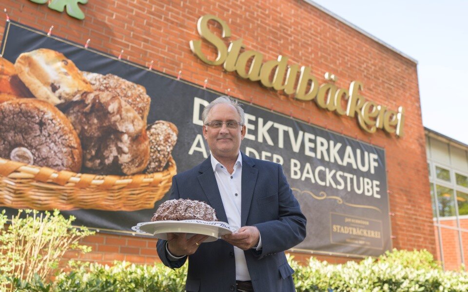 Geschäftsführer mit Kuchen vor der Stadtbäckerei Oldenburg
