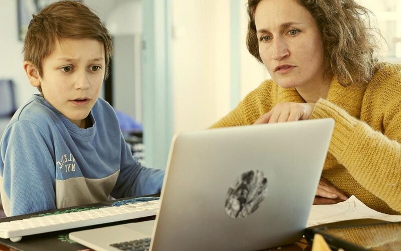 Mutter und Sohn sitzen beim Homeschooling ratlos vor Laptop zu Hause