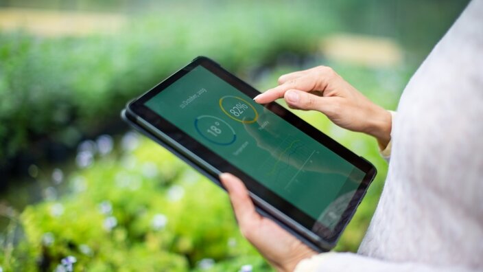 Eine Frau prüft auf einem Tablet die Daten zu Ihrem grünen Produkt