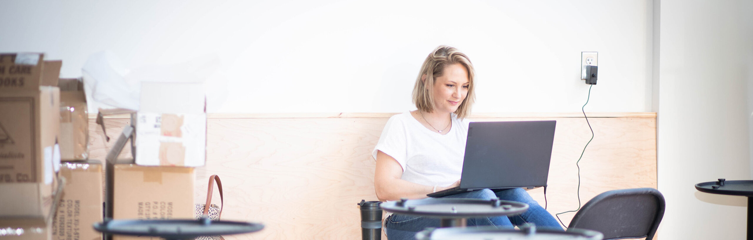 Eine Unternehmerin, die mit Laptop in einem Geschäftsraum sitzt, der gerade umgebaut wird