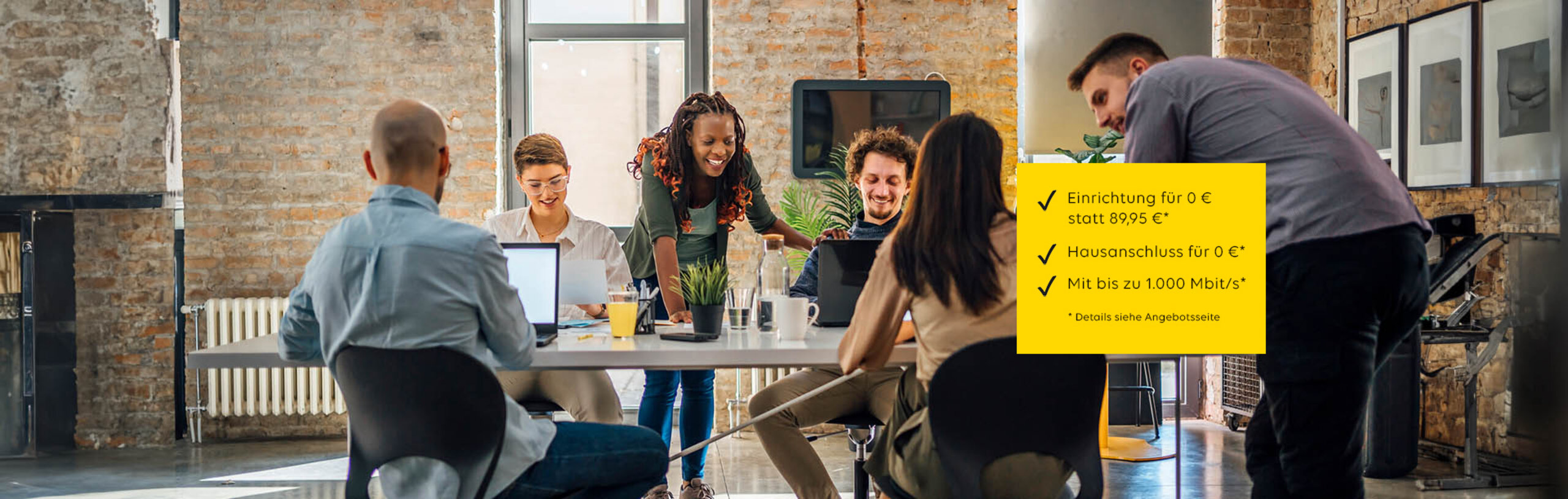 Jungen Menschen, die mit Computern rund um einen Schreibtisch arbeiten