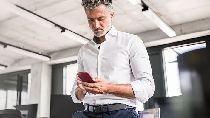 Ein Mann checkt seine Smartphone während der Arbeit