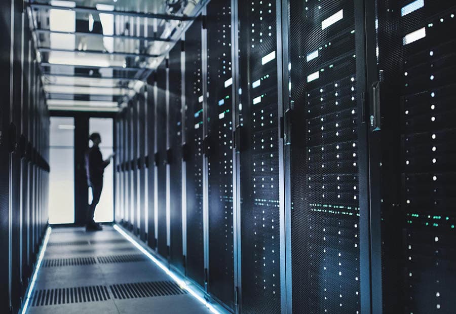 Ein Rechenzentrum, in dem im Hintergrund jemand an einem Serverschrank arbeitet