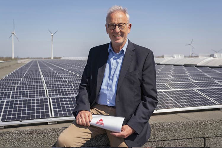 Der Hase-Geschäftsführer sitzend vor einer PV-Anlage