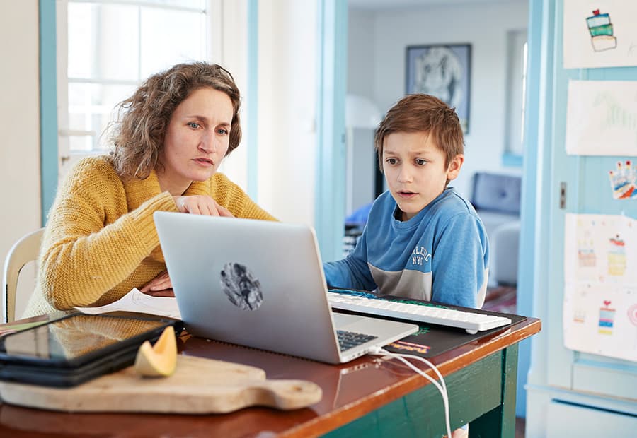 Mutter und Sohn sitzen am Küchentisch am Laptop