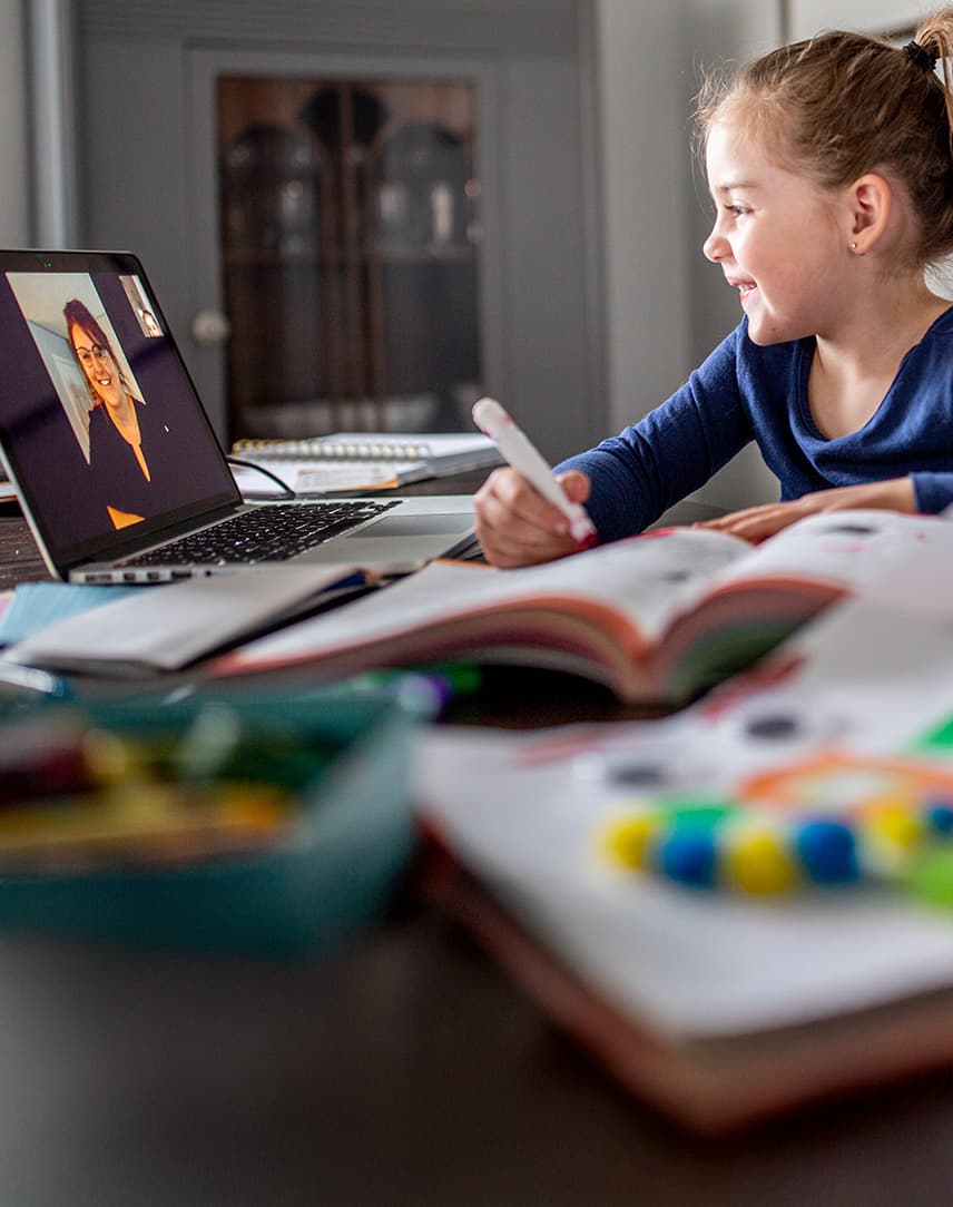 Ein Mädchen interagiert am Rechner mit ihrer Lehrerin.