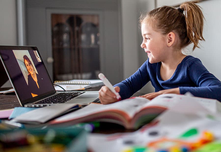 Ein Mädchen interagiert am Rechner mit ihrer Lehrerin.