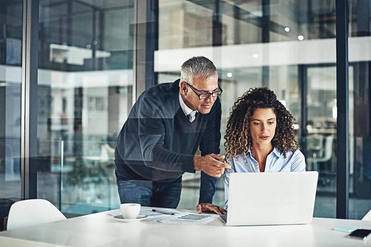 Ein Mann und eine Frau besprechen etwas bei der Arbeit an einem Computer.
