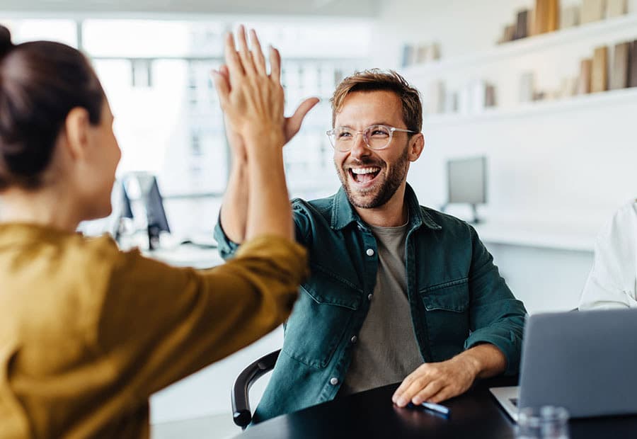 Eine Frau und ein Mann, die sich im Büro abklatschen