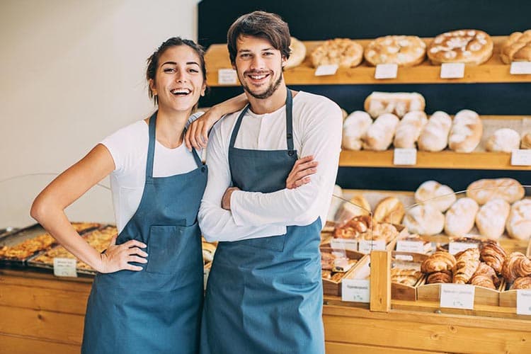 Eine lachende Bäckerin und ein Bäcker in einer Bäckerei 