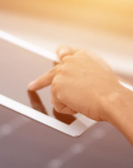 Eine Person bedient ein Tablet, im Hintergrund PV-Module